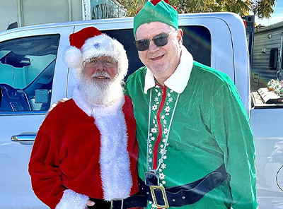 A person dressed as Santa Claus and a person dressed as a Christmas elf posing together at the Yucaipa Christmas Parade.